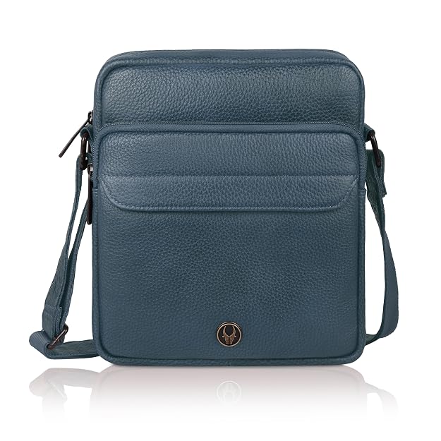 A dark blue pebbled leather crossbody bag with a front pocket and a small circular gold logo, shown on a white background with a reflection.