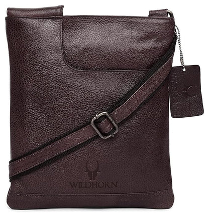 Black textured leather crossbody bag with a diagonal strap, a hanging brand tag, and a debossed logo on the front, shown on a white background.