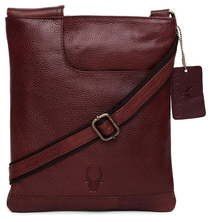 A maroon pebbled leather crossbody bag with a matching adjustable shoulder strap and a hanging leather brand tag, shown on a plain white background.