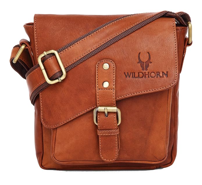 A brown leather crossbody bag with brass hardware, featuring a front flap with a buckle strap and the brand name 'WILDHORN' embossed on the side, set against a plain white background.