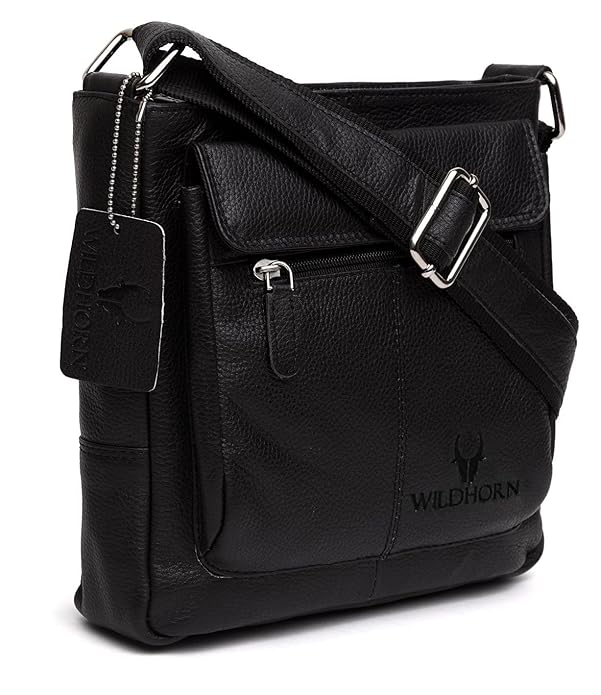 A black pebbled leather crossbody bag with a front flap pocket, silver-tone buckle strap, and embossed Wildhorn logo on the lower right front, shown on a white background.