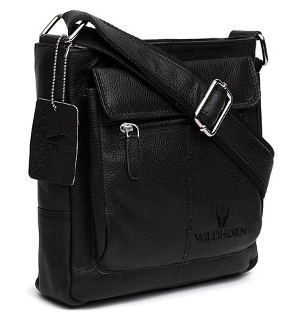 A black pebbled leather crossbody bag with a front flap pocket, silver-tone buckle strap, and embossed Wildhorn logo on the lower right front, shown on a white background.