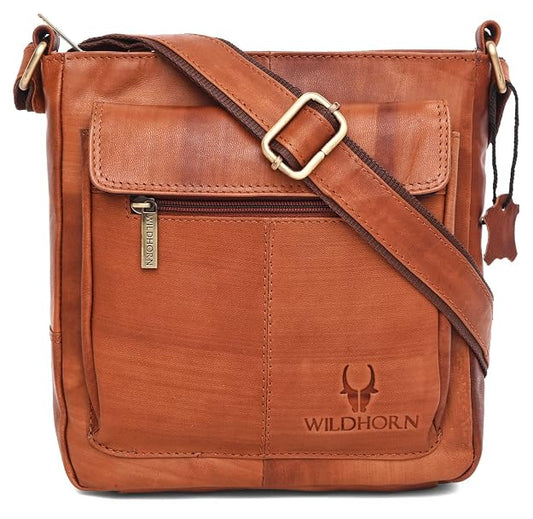 A brown leather crossbody bag with a front zippered pocket, adjustable shoulder strap, and a debossed WILDHORN logo on the lower front, shown on a white background.